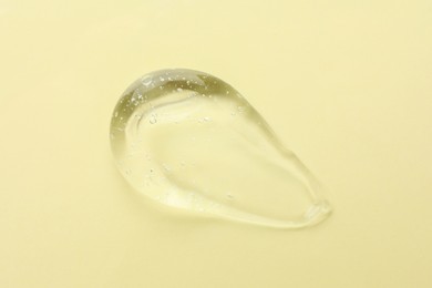 Clear cosmetic gel on yellow background, top view