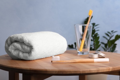 Set with bamboo toothbrushes and towel on table