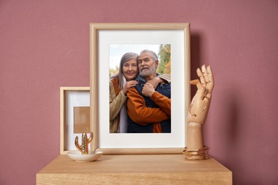 Image of Family portrait of man and woman in photo frame on table near color wall