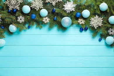 Fir branches with Christmas decoration on light blue wooden background, flat lay. Space for text