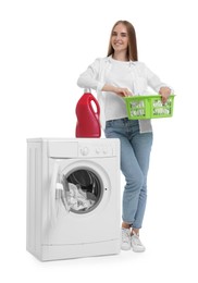 Beautiful young woman with laundry basket near washing machine on white background