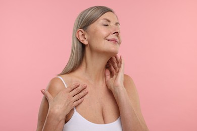 Photo of Beautiful woman touching her neck on pink background