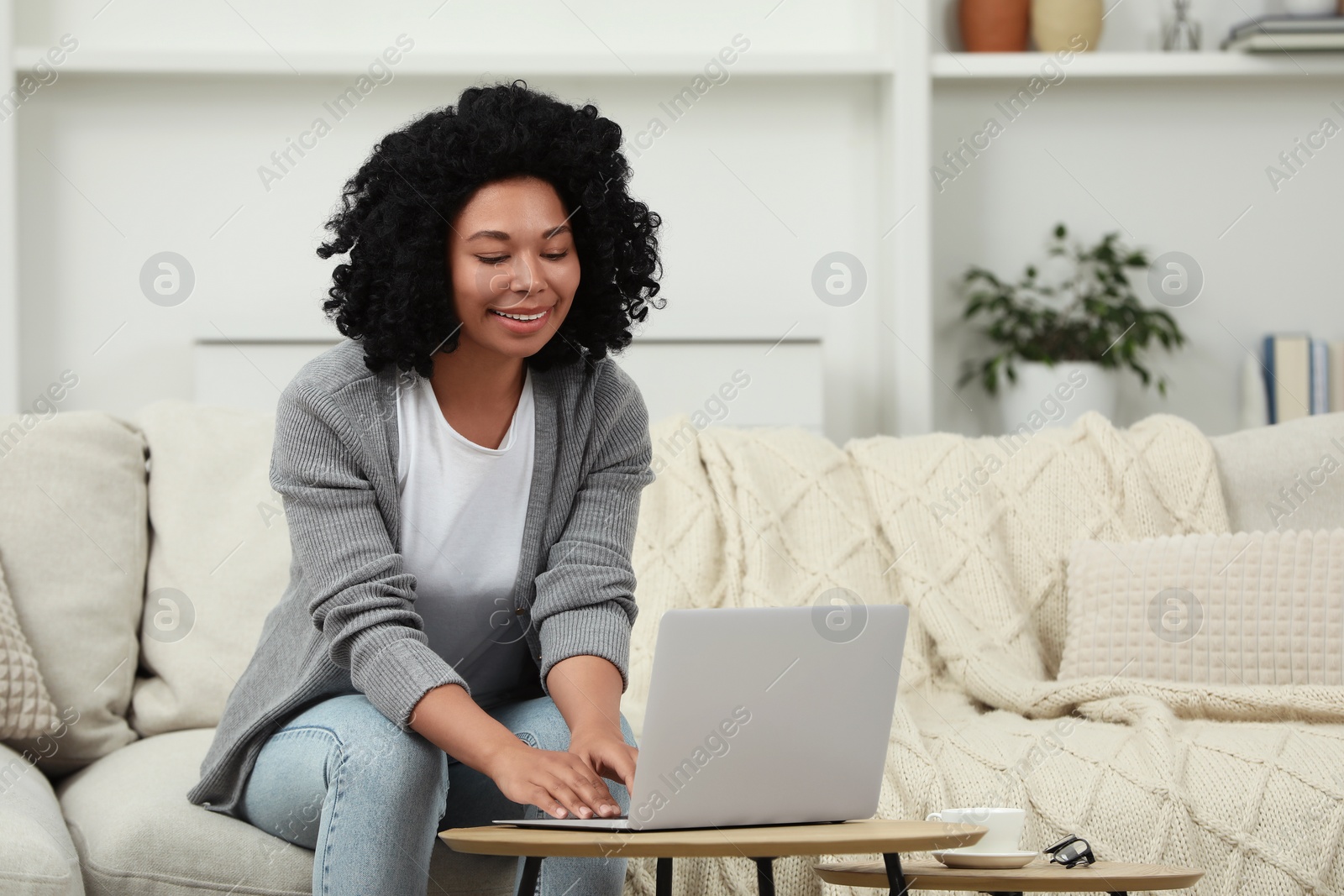 Photo of Happy young woman using laptop at wooden coffee table indoors. Space for text