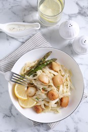 Photo of Delicious scallop pasta served on white marble table, flat lay