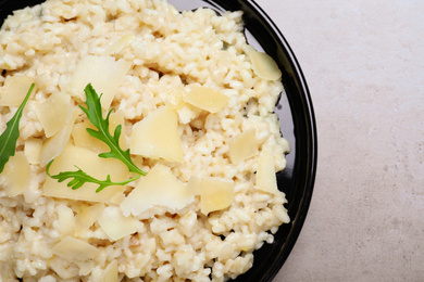 Delicious risotto with cheese on grey table, top view