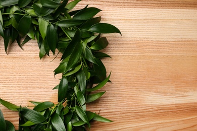 Beautiful handmade mistletoe wreath on wooden table, top view. Space for text