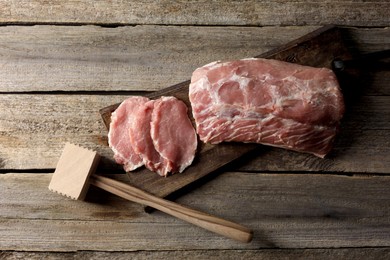 Photo of Cooking schnitzel. Raw pork meat and tenderizer on wooden table, top view