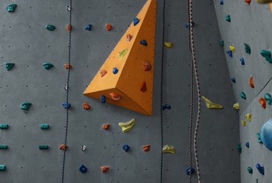 Photo of Climbing wall with holds and ropes in gym. Extreme sport