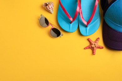 Flat lay composition with different beach accessories on yellow background. Space for text