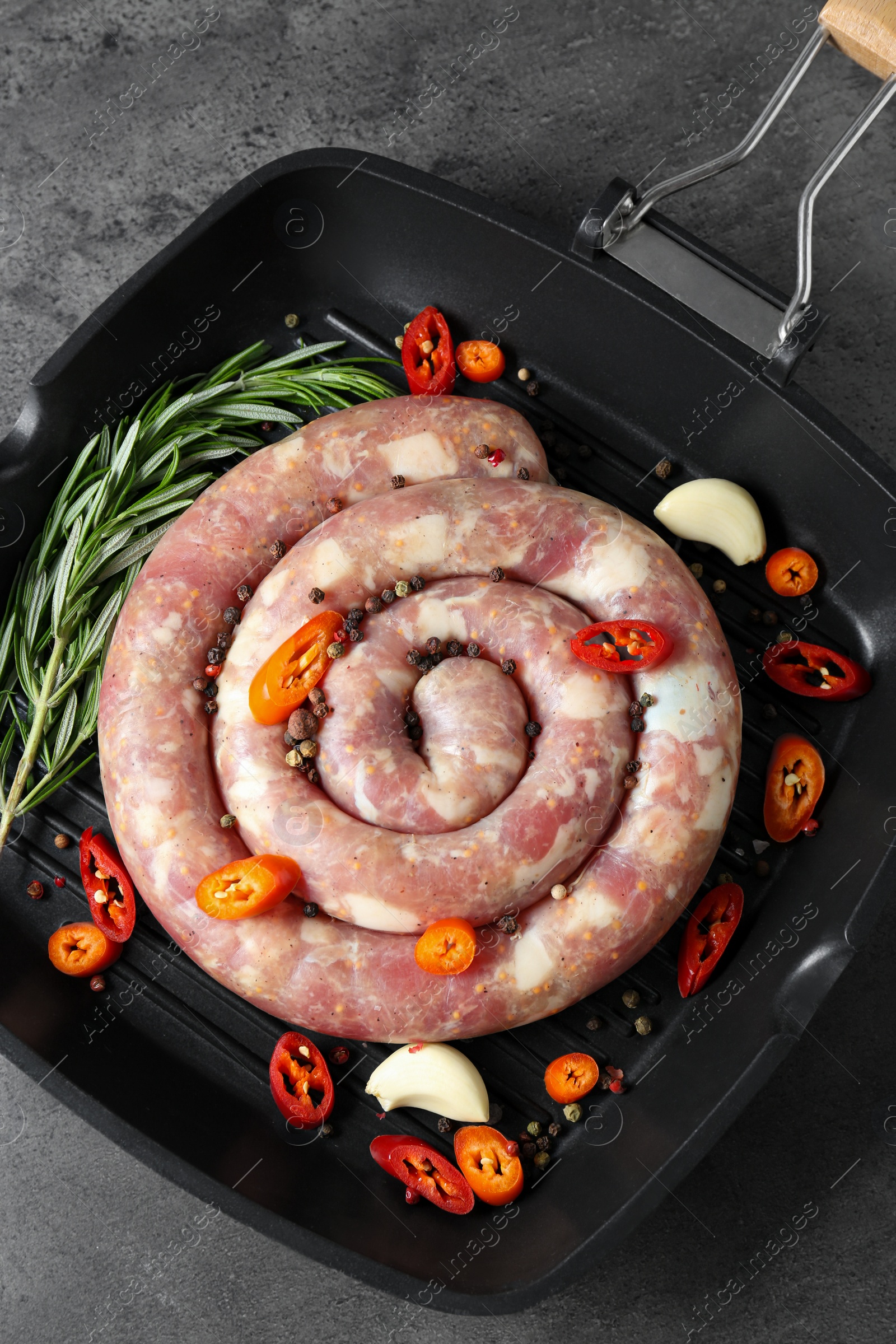 Photo of Pan with raw homemade sausage, chili pepper, garlic and rosemary on grey table, top view