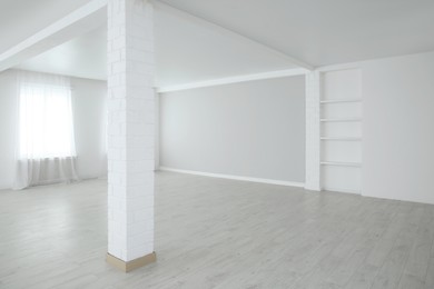 Empty room with large window and laminated floor