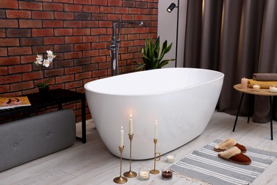 Photo of Stylish bathroom interior with ceramic tub and burning candles