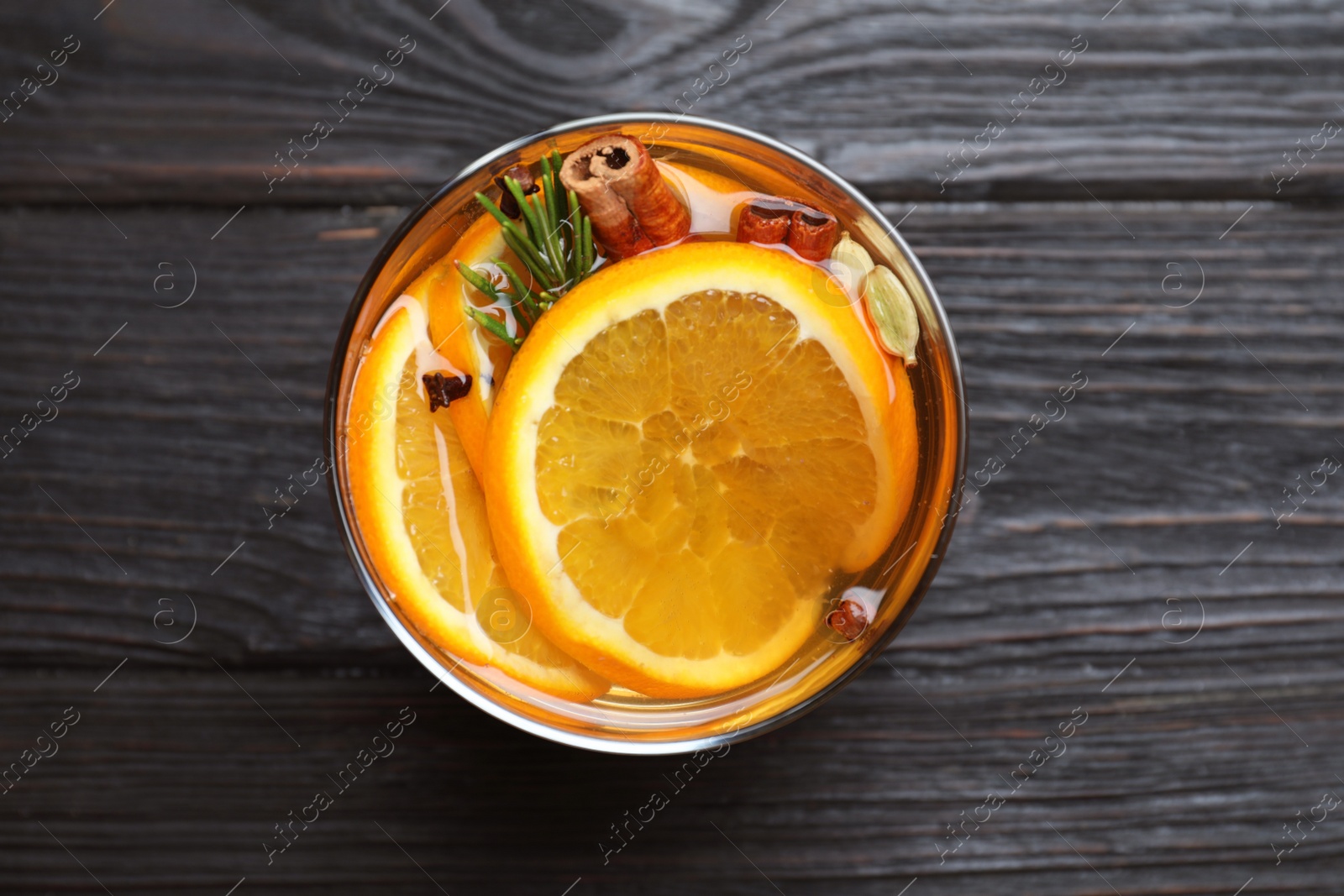 Photo of Aromatic mulled wine on black wooden table, top view