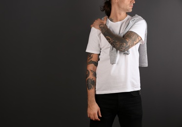 Young man with stylish tattoos on grey background. Space for text