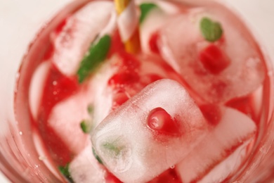 Photo of Ice cubes with pomegranate seeds in drink, closeup