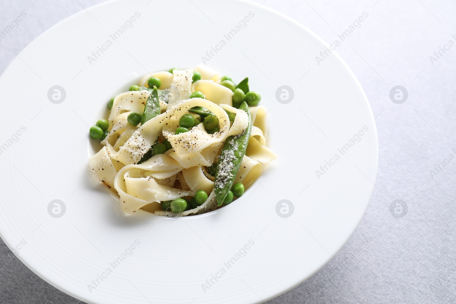 Photo of Delicious pasta with green peas on grey table