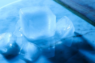 Photo of Crystal clear ice cubes on marble board, color tone effect