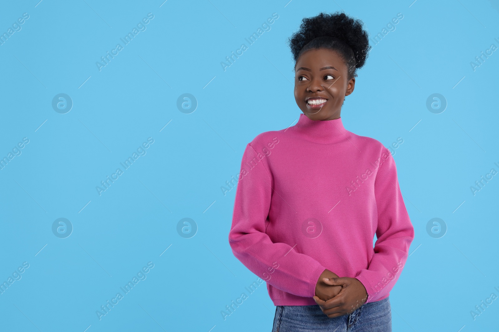 Photo of Portrait of happy young woman on light blue background. Space for text