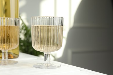 Photo of Alcohol drink in glasses on white wooden table indoors, closeup. Space for text