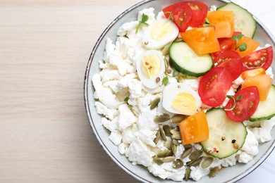 Photo of Fresh cottage cheese with vegetables, seeds and eggs in bowl on wooden table, top view