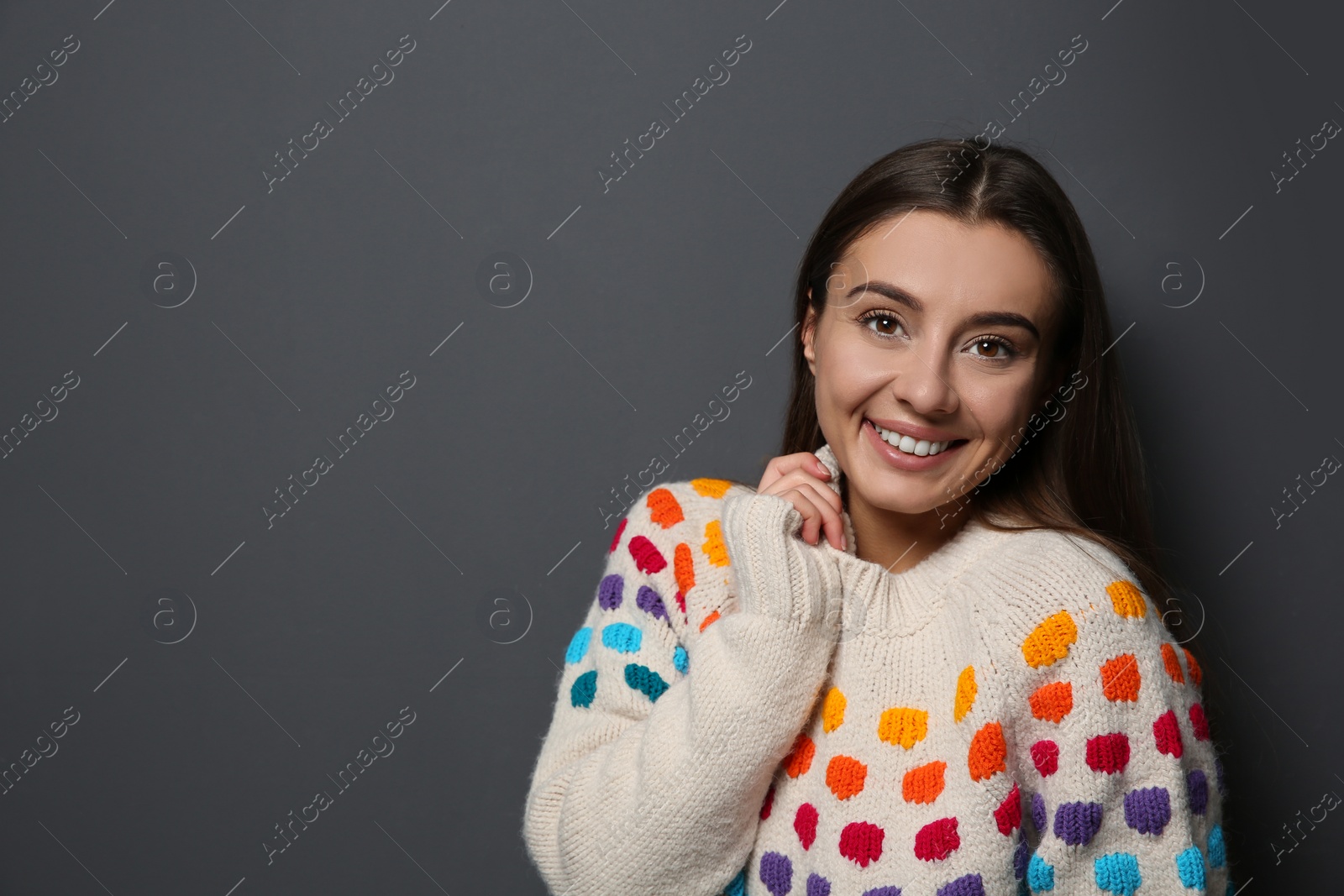 Photo of Beautiful young woman in warm sweater on dark background. Space for text