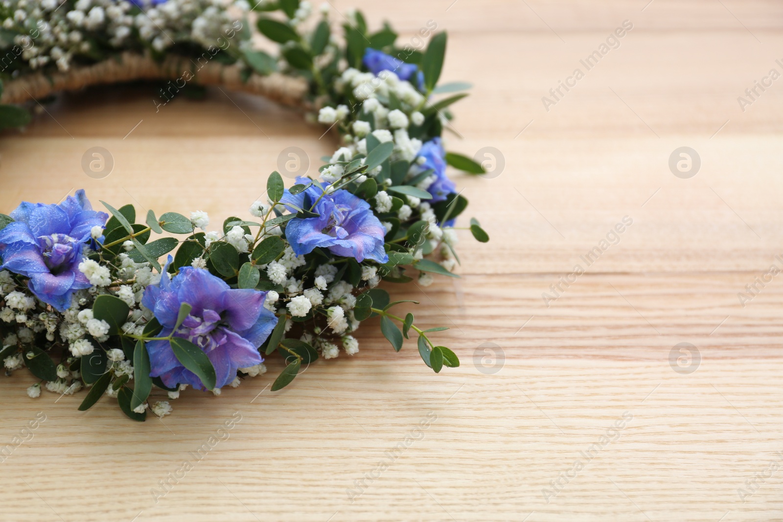 Photo of Beautiful flower wreath on wooden background, closeup. Space for text