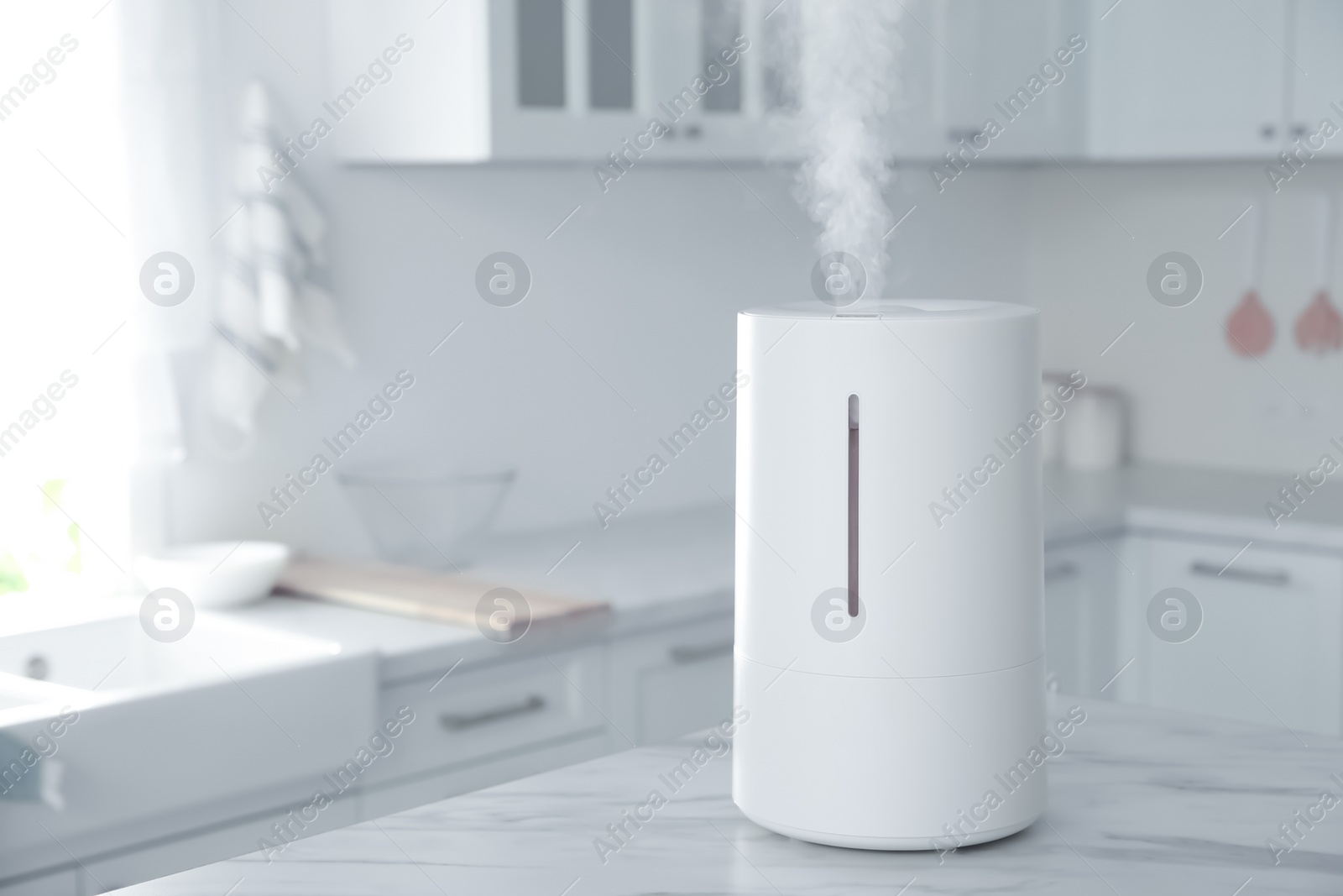 Photo of Modern air humidifier on table in kitchen. Space for text