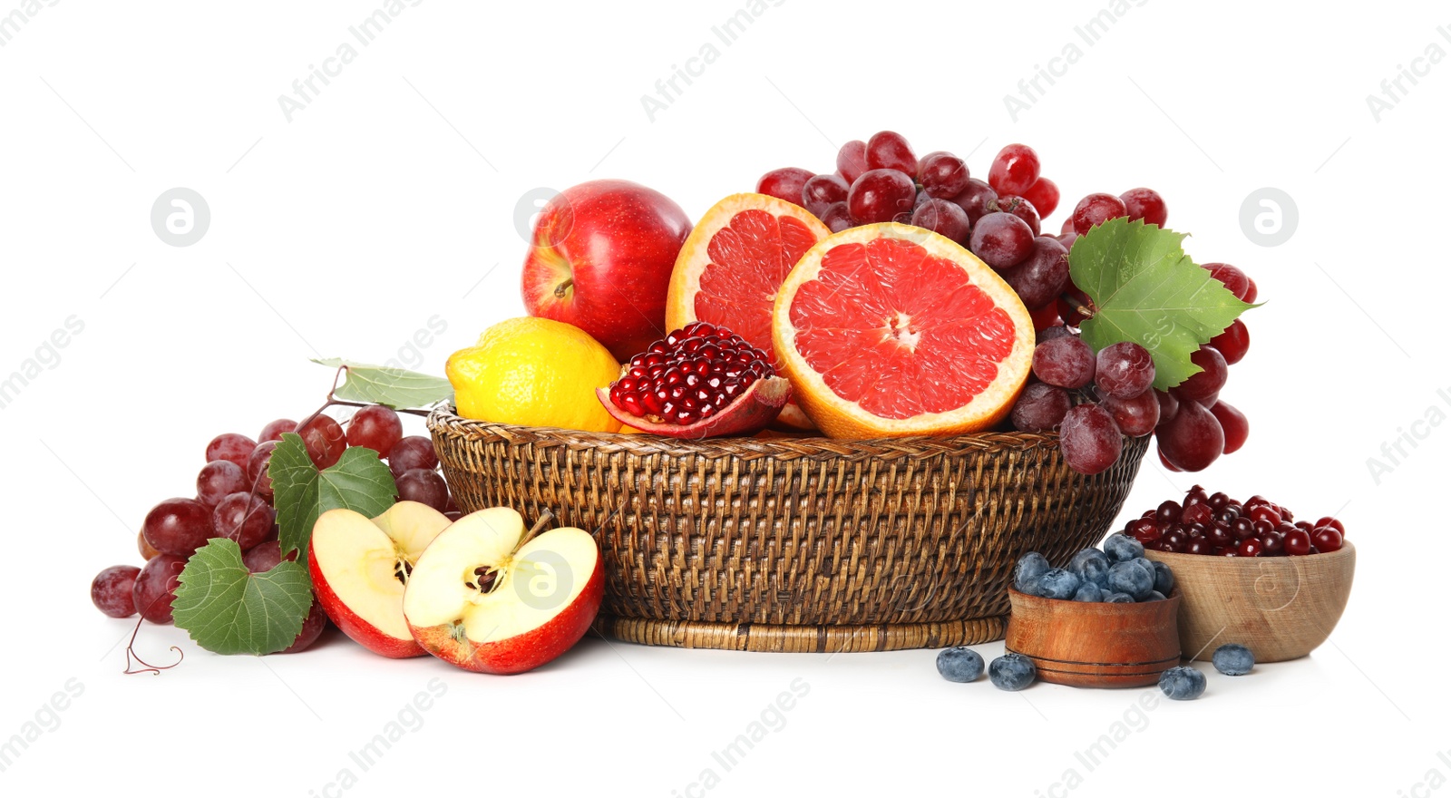 Photo of Wicker basket with different fruits and berries on white background