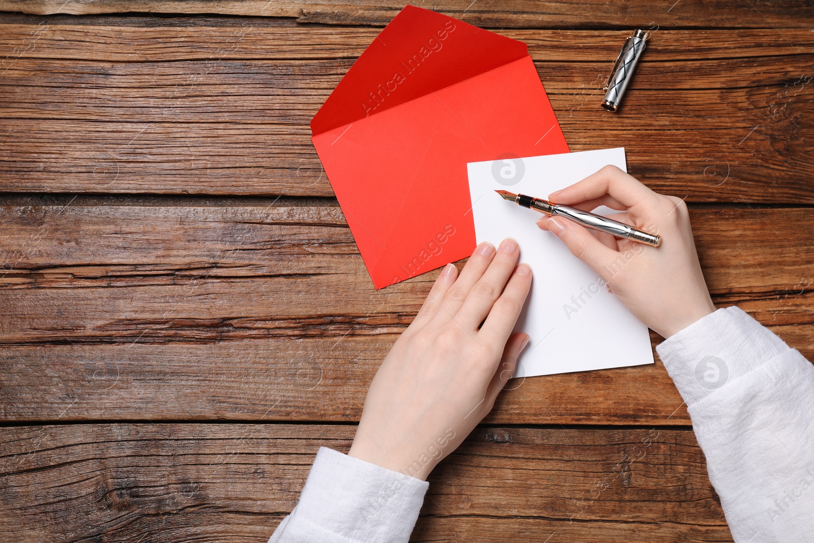 Photo of Woman writing letter at wooden table, top view. Space for text