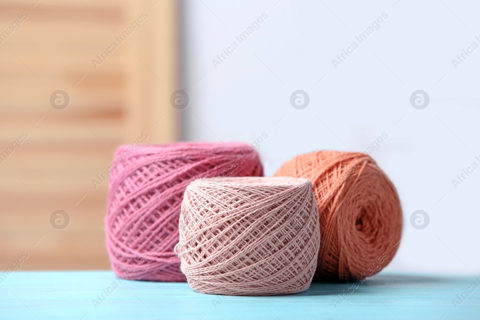 Photo of Colorful clews of threads on table against blurred background