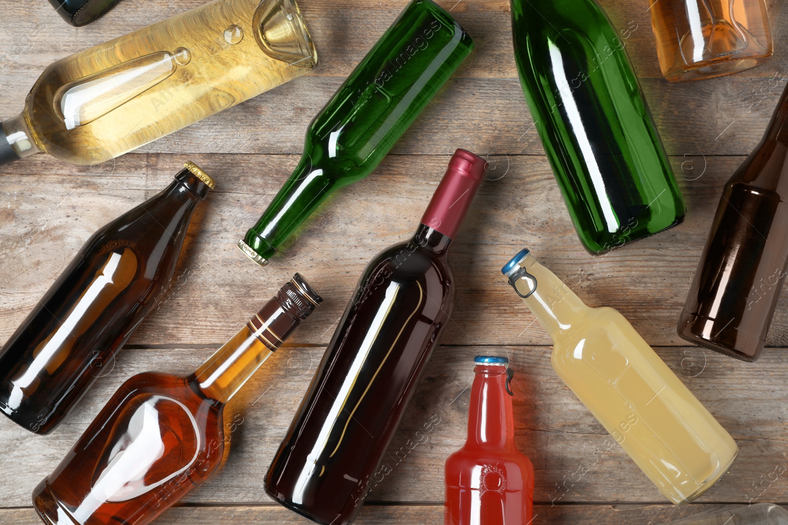 Photo of Bottles with different alcoholic drinks on wooden background, flat lay