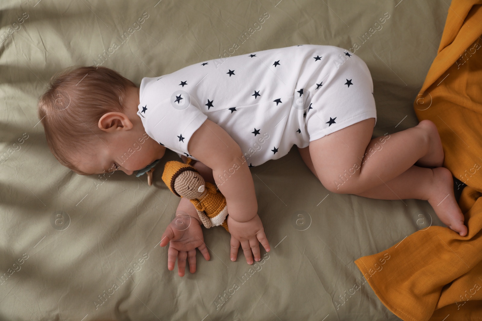 Photo of Adorable little baby with pacifier and toy sleeping on bed, top view