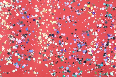 Photo of Shiny glitter on red background, top view