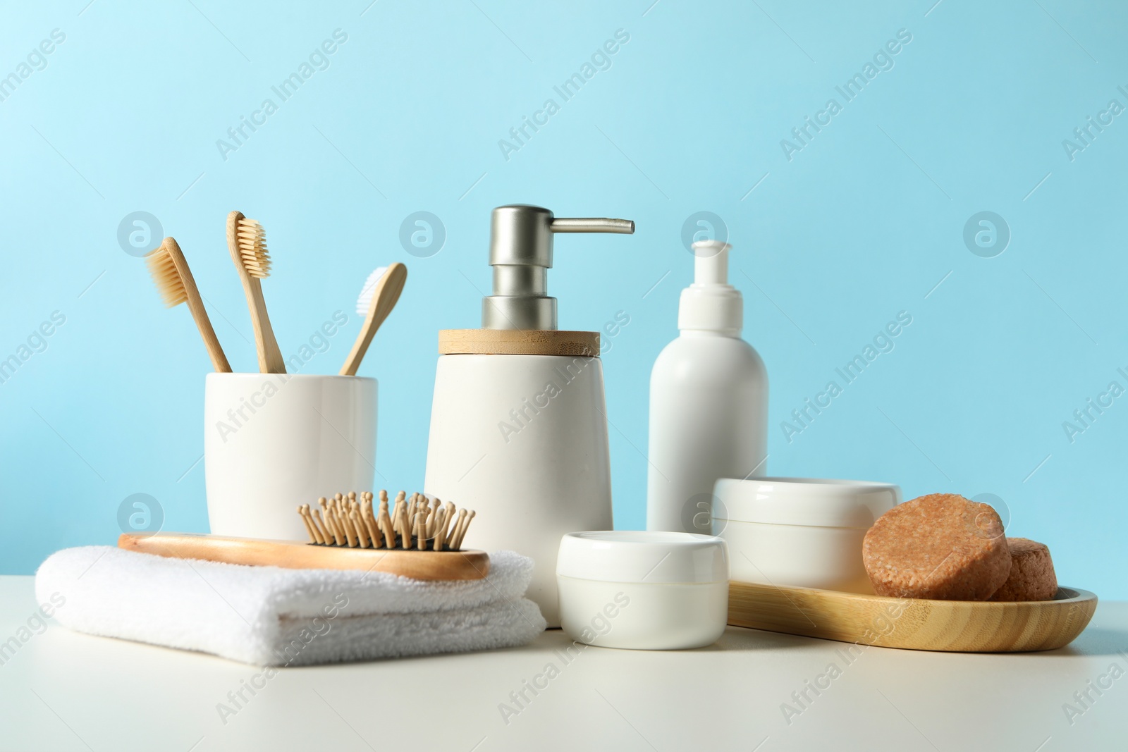 Photo of Different bath accessories on white table against light blue background