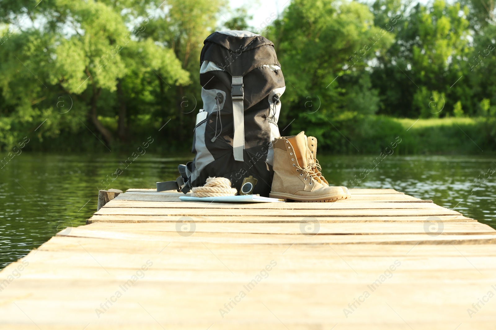 Photo of Backpack and camping equipment on wooden pier near river