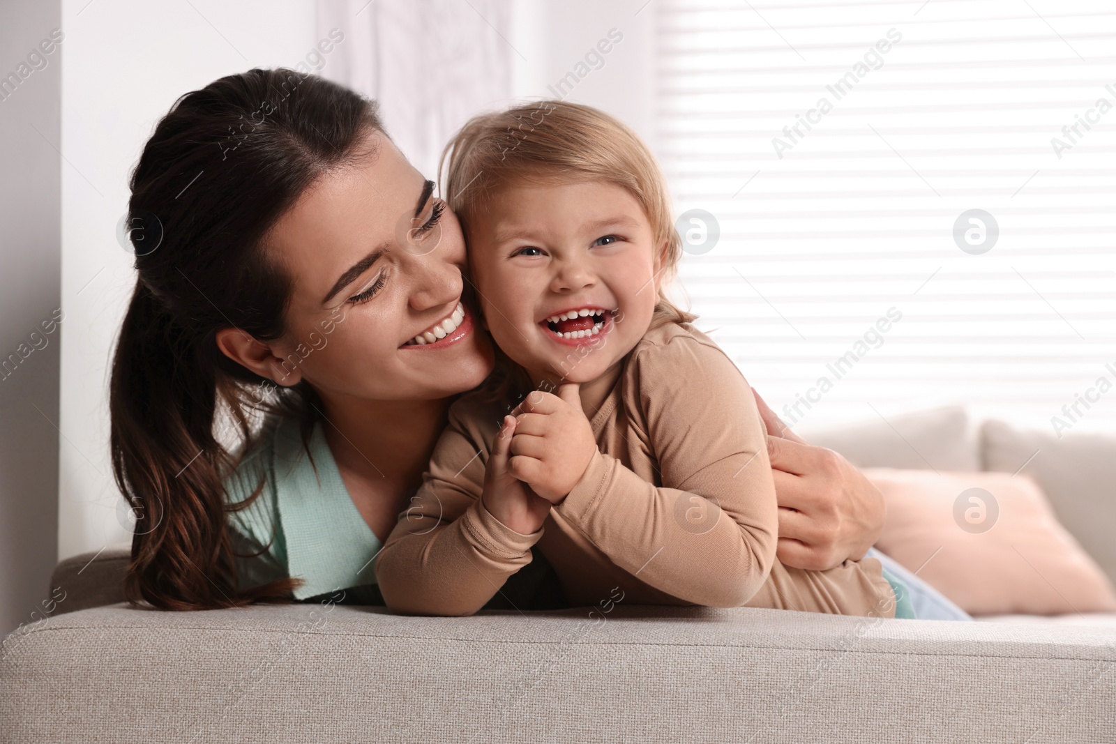 Photo of Mother with her cute little daughter on sofa at home