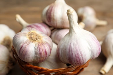 Photo of Fresh organic garlic in wicker basket, closeup