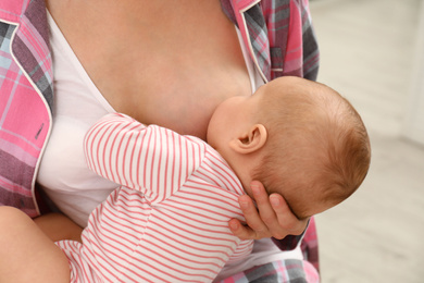 Young woman breastfeeding her little baby at home, closeup