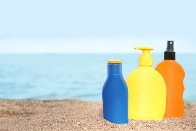 Bottles of sun protection body cream on beach, space for design