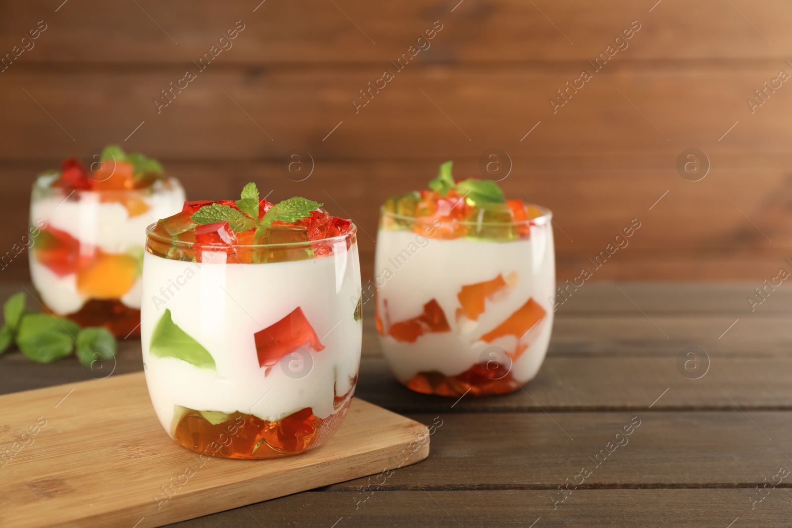 Photo of Delicious broken glass jelly dessert on wooden table, space for text