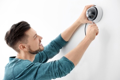 Technician installing CCTV camera on wall indoors