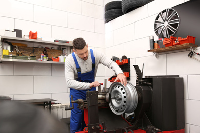 Mechanic working with car disk lathe machine at tire service