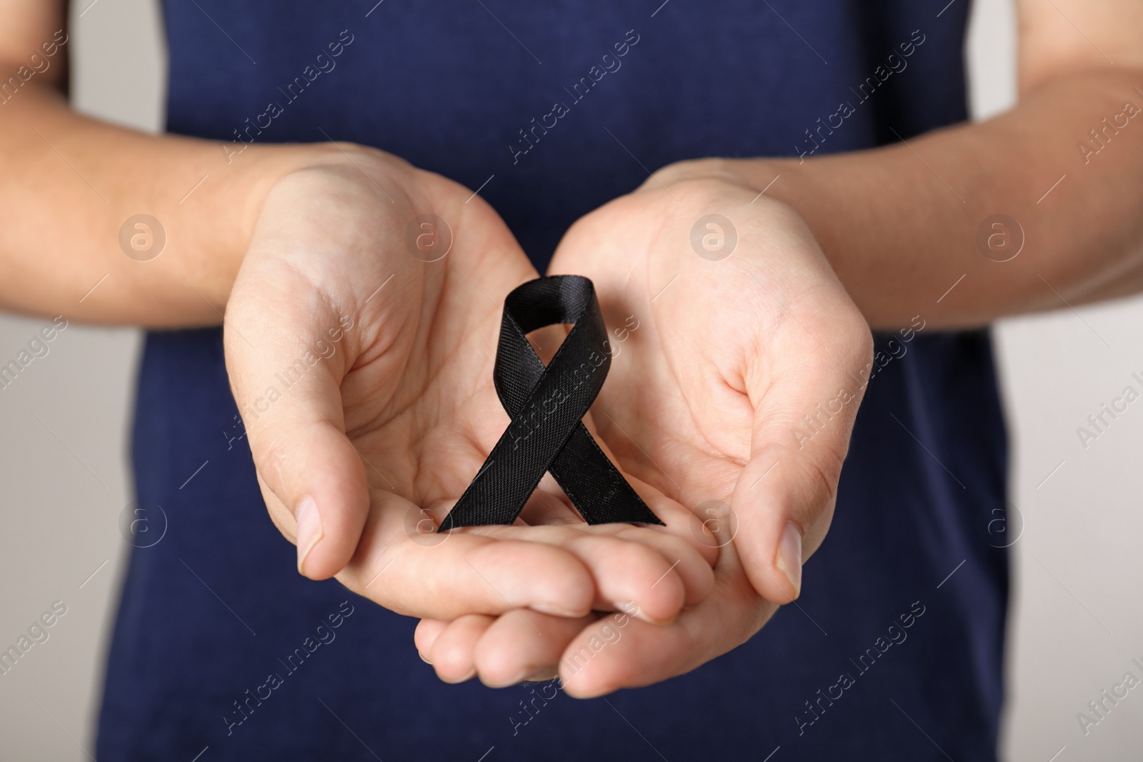 Photo of Young woman holding black ribbon, closeup. Funeral symbol