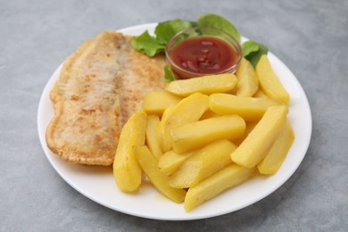 Photo of Delicious fish and chips with ketchup and lettuce on gray table, closeup