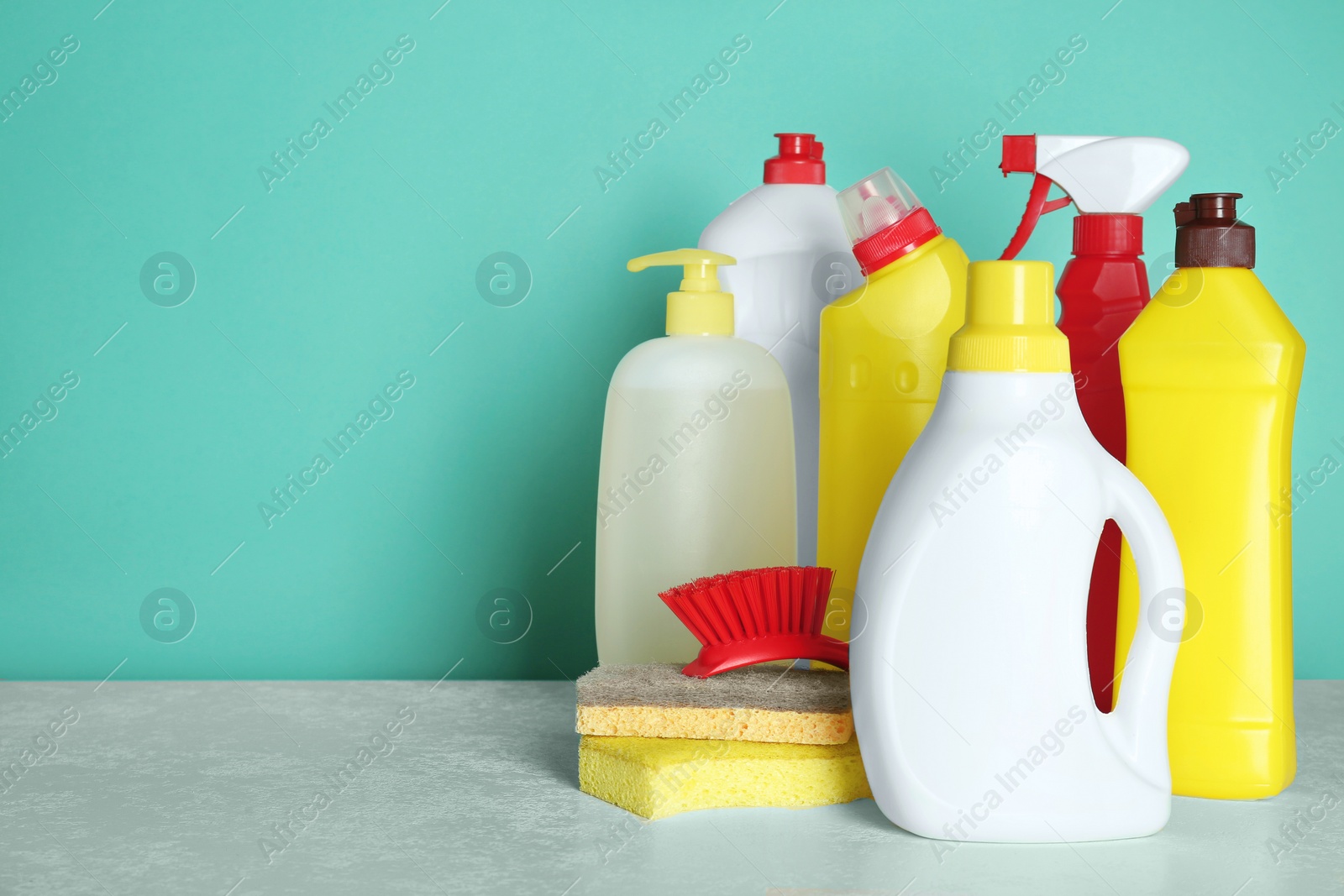 Photo of Different cleaning supplies and tools on table against turquoise background, space for text