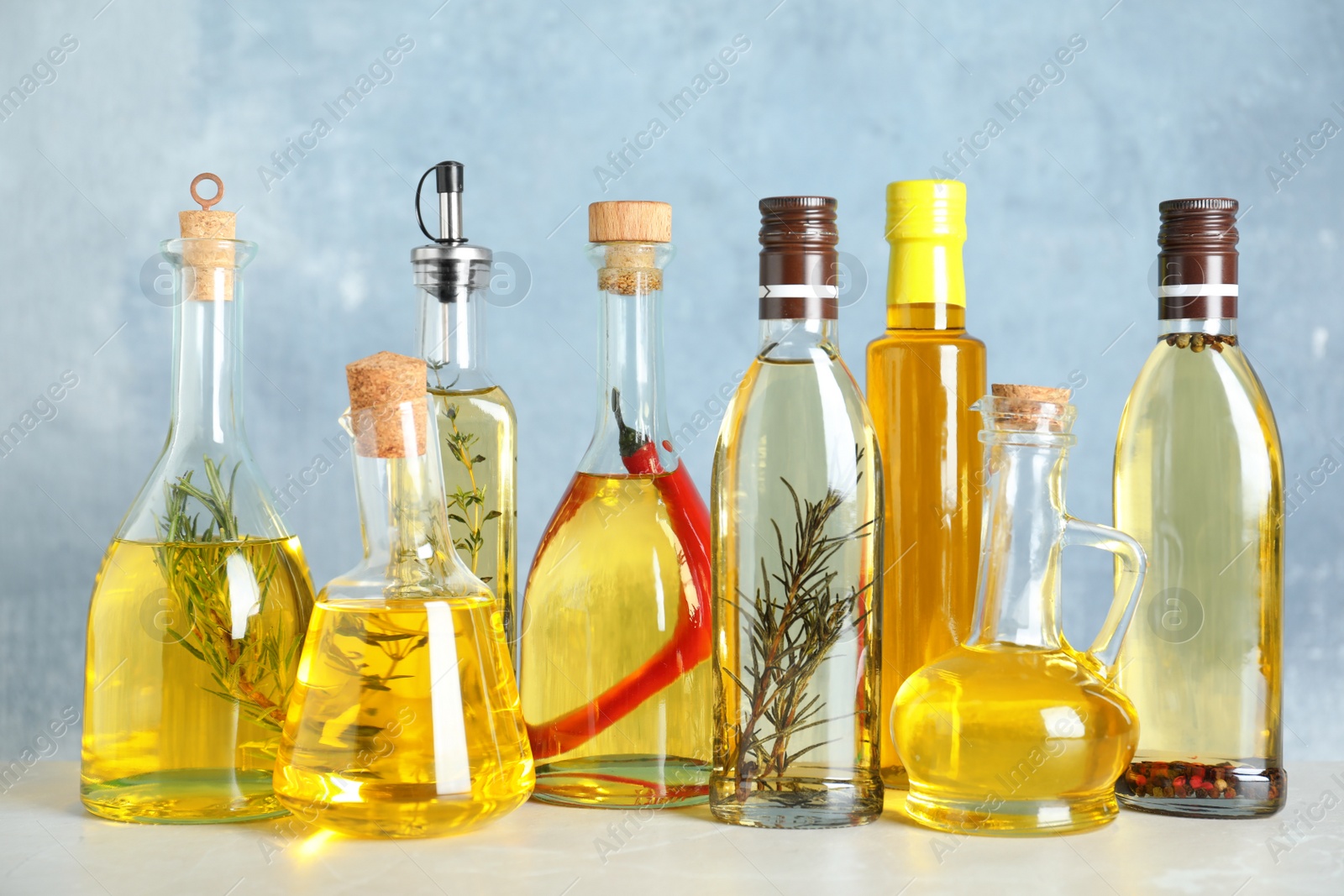 Photo of Different sorts of cooking oil in bottles on light grey table