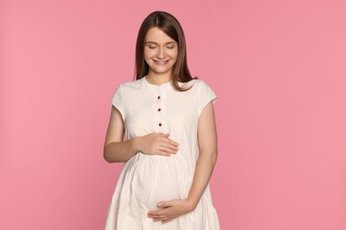 Photo of Happy young pregnant woman on pink background