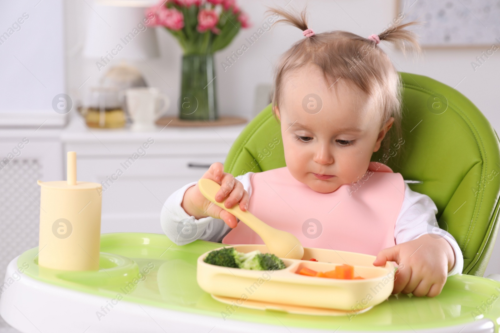 Photo of Cute little baby eating food in high chair at home