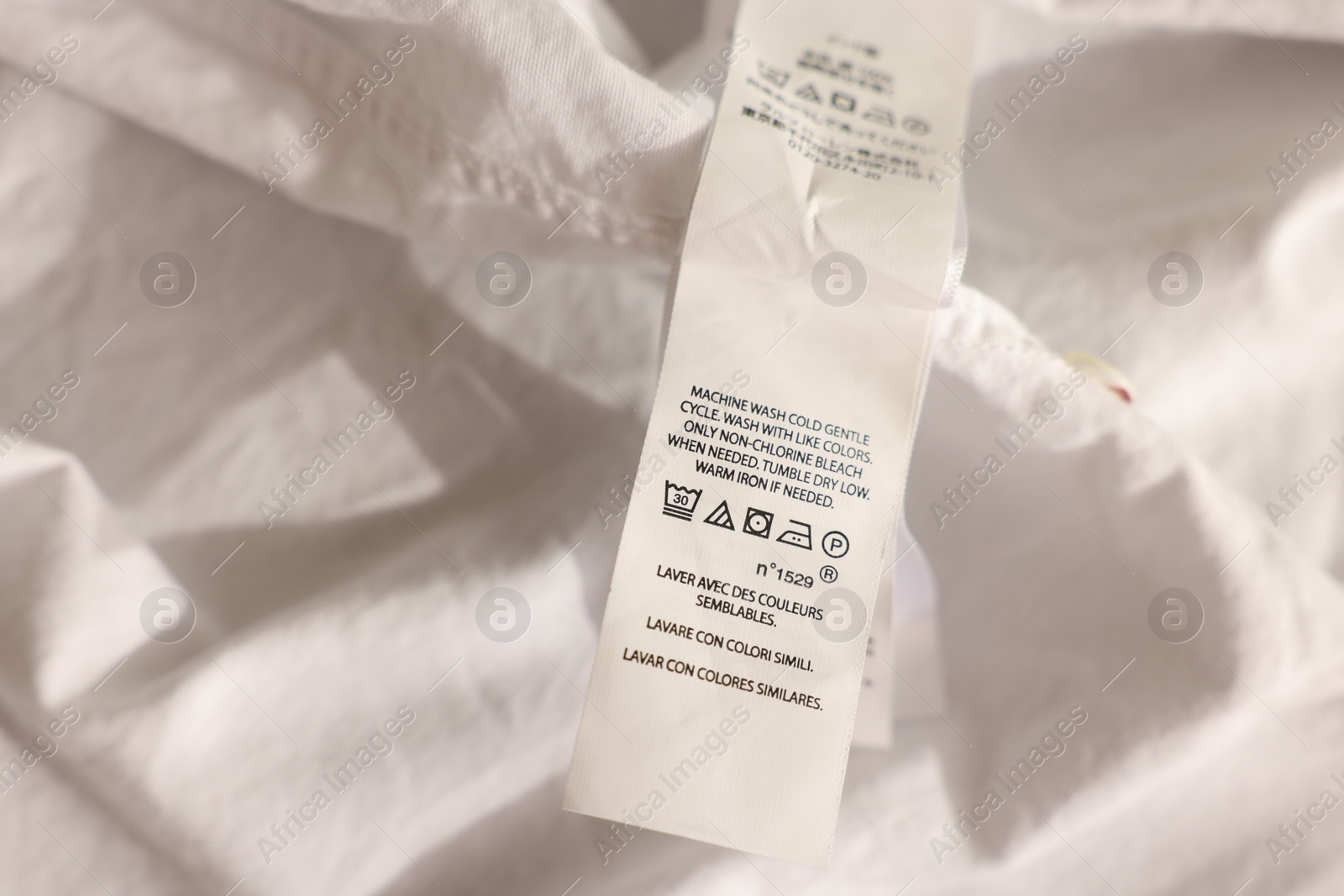 Photo of Clothing label in different languages on white garment, closeup