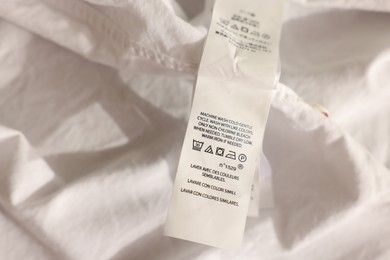 Clothing label in different languages on white garment, closeup